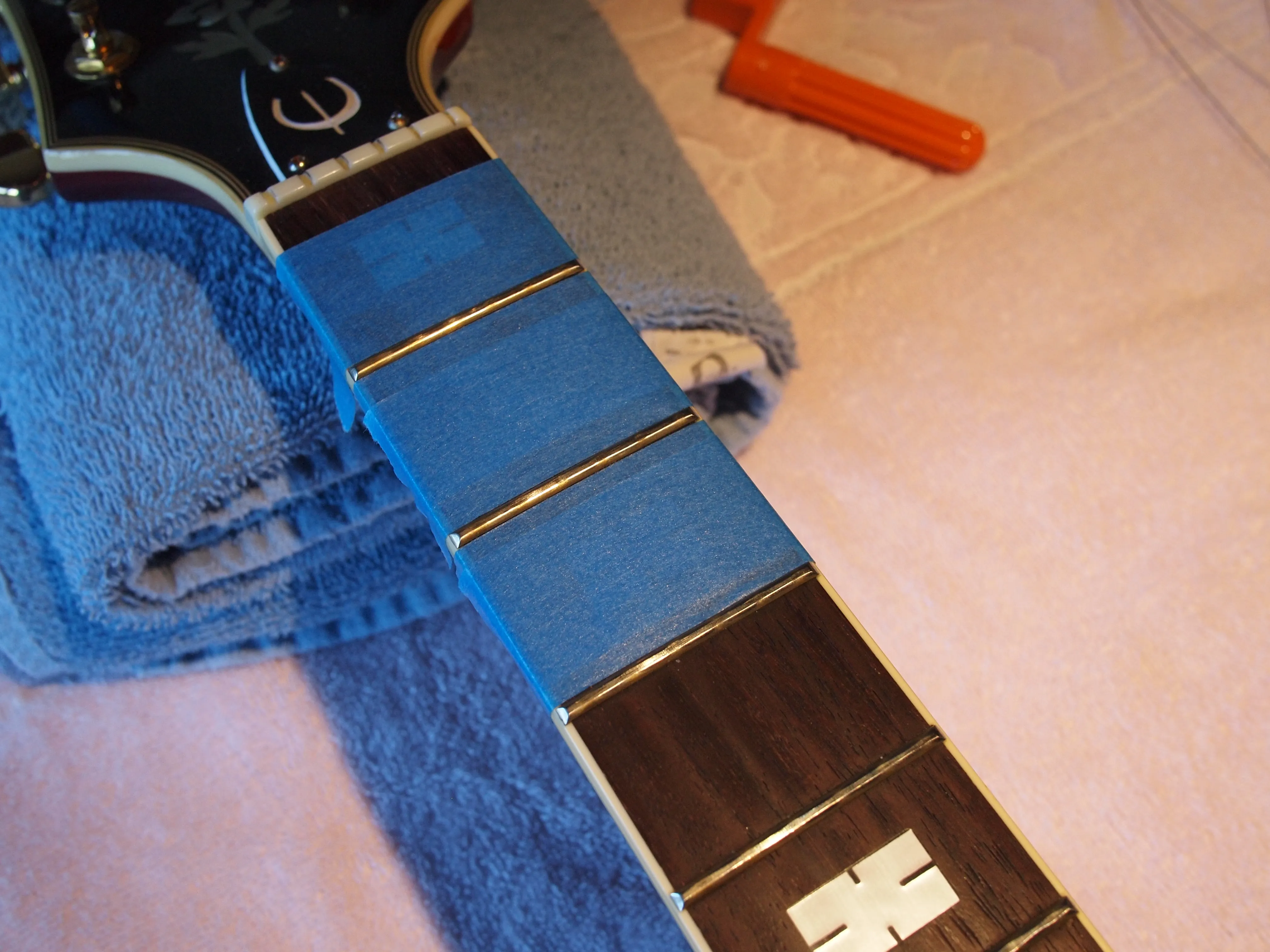 Use "blue" tape to protect the fretboard and neck.  Blue tape is not as sticky as regular masking tape.